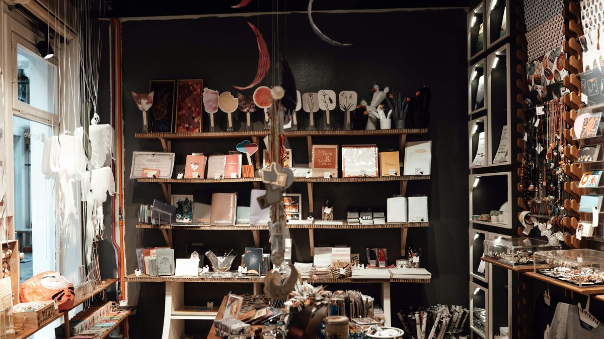 An eclectic small artisan store with shelves of handmade prints, cards, notebooks, and jewelry on display